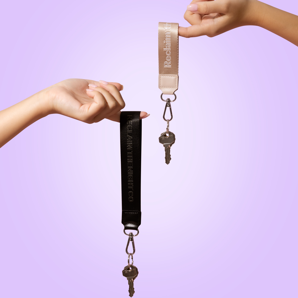 Keychain with key held between two hands against a purple background
